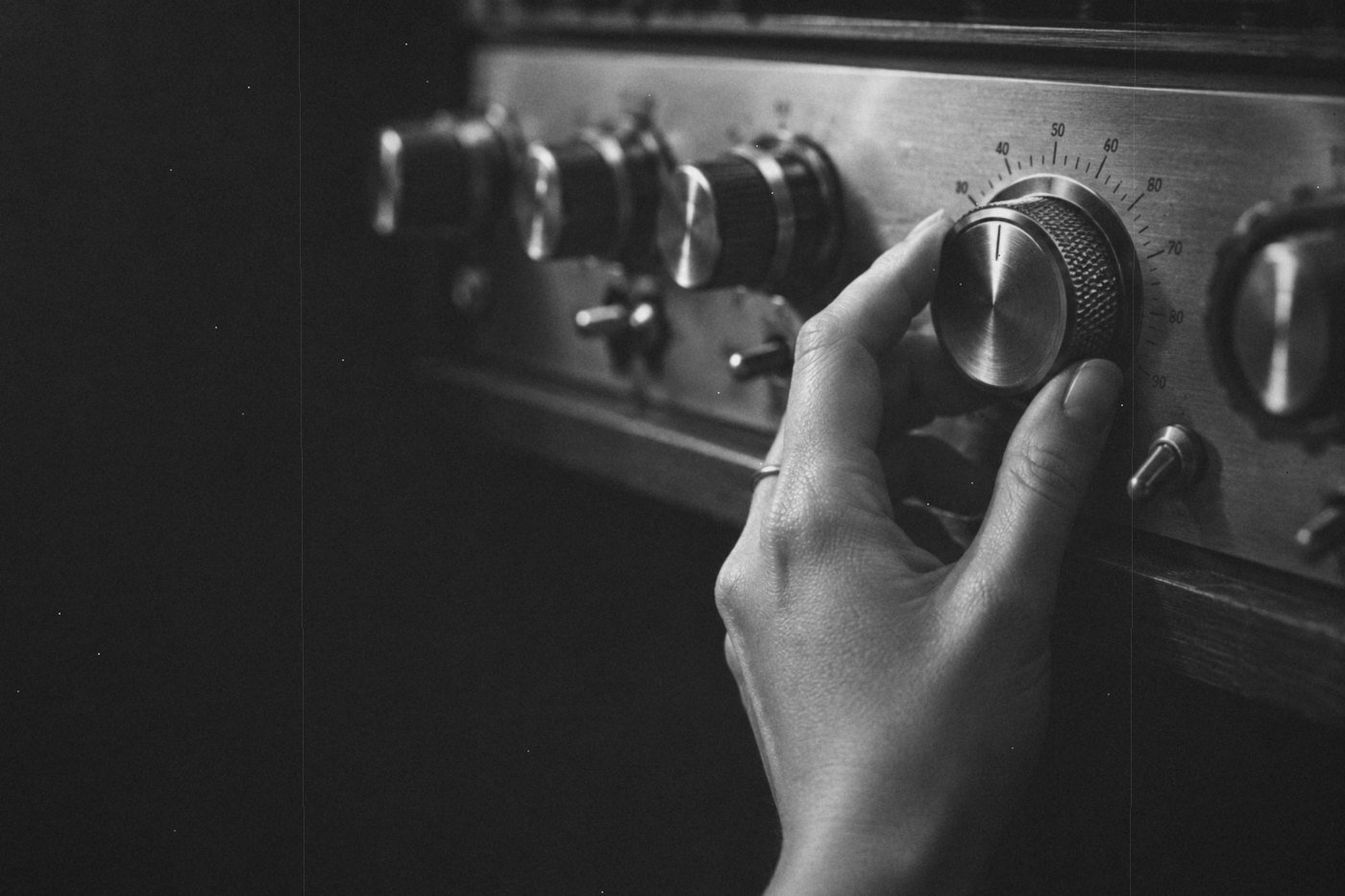 Mano ajustando una perilla metálica en un equipo de audio antiguo